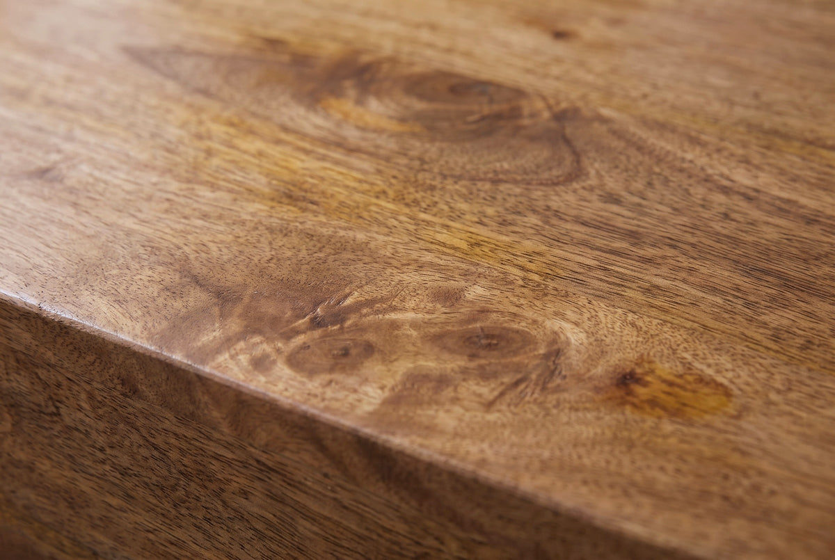 Close-up of the golden-brown mango wood on the Mamoiada nightstand: swirling grain with darker knots running to an eased edge