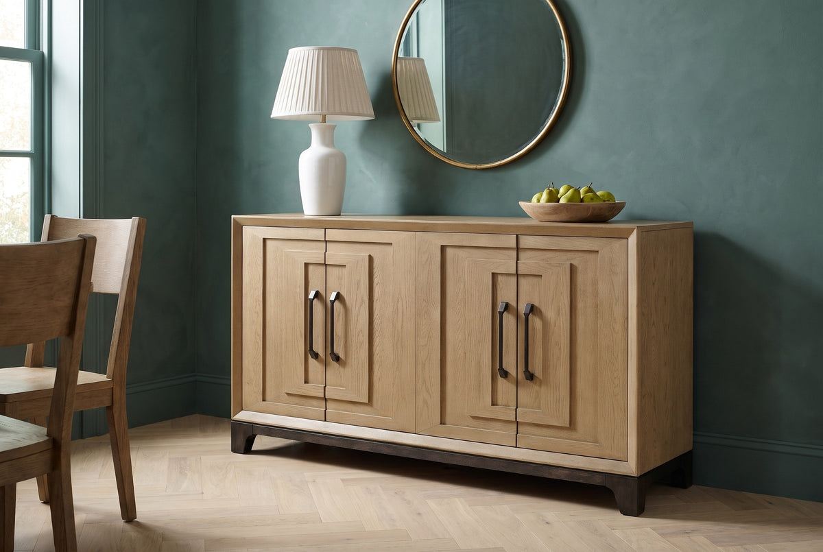 Maratea oak sideboard with a ceramic lamp, a round mirror and a bowl of pears against a deep teal plaster wall in a Charleston dining room, with a herringbone oak floor