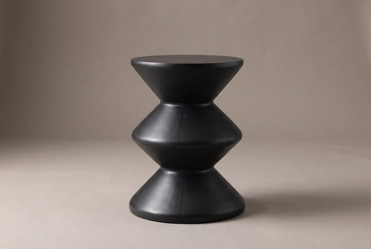 The Marineo side table from the side: a round top on a cone, a middle double cone and a cone base, zigzagging wide, narrow, wide, narrow, wide