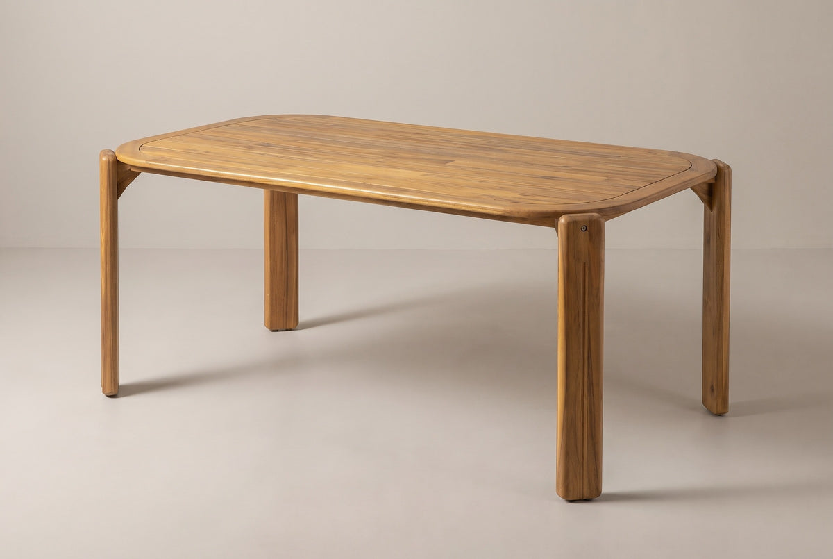 The Mazara acacia outdoor dining table in a teak finish, three-quarter view on a light studio backdrop