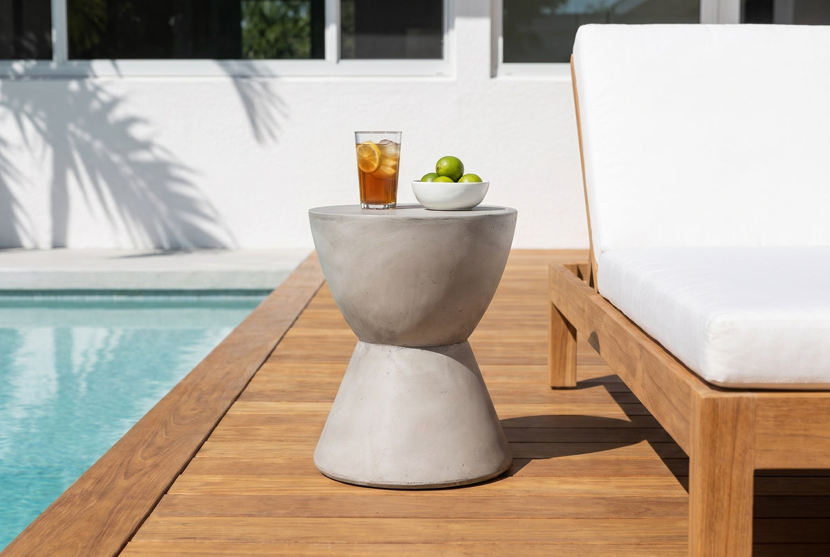 Mazzaro concrete side table on a teak pool deck in Sarasota beside a lounge chair with a white cushion, a glass of iced tea and limes on top (chair and decor not included)
