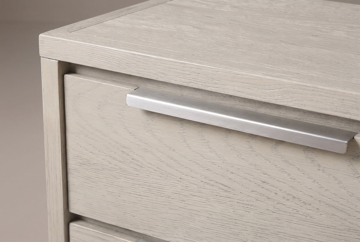 The upper drawer of the Melfi nightstand: one long brushed metal pull along the top edge with its lip folding down over the wire-brushed oak front
