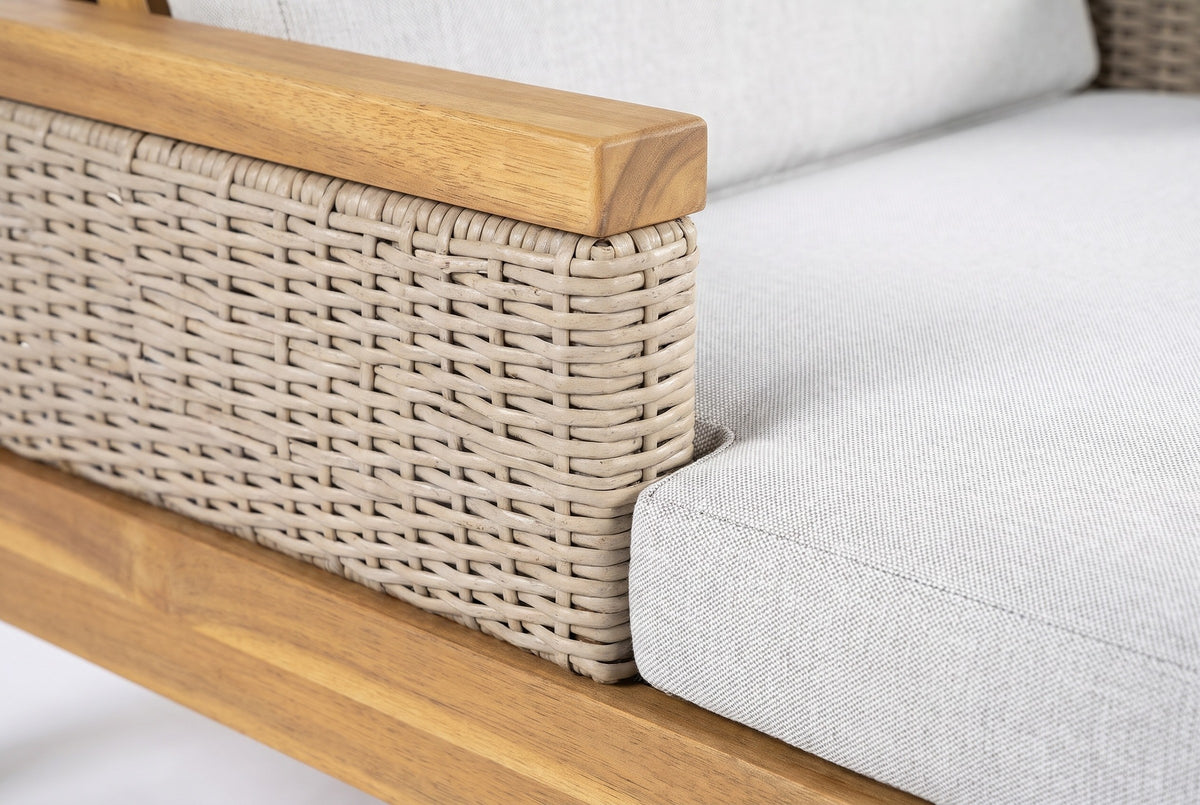 Close-up of a Menfi armrest: the flat acacia top rail and the light grey handwoven wicker beside the cushion