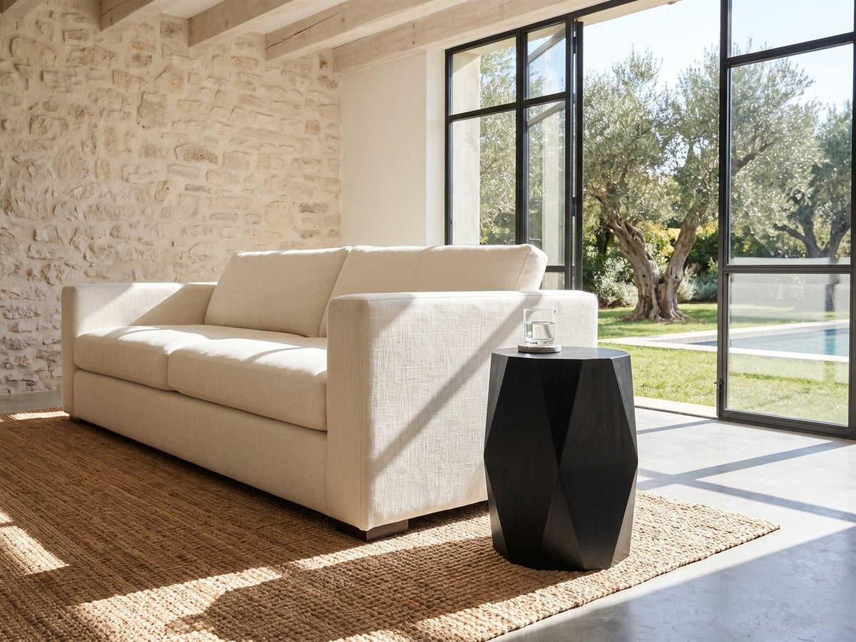 Miglionico Black Mango Wood Faceted Drum Side Table beside a linen sofa in a poolside villa