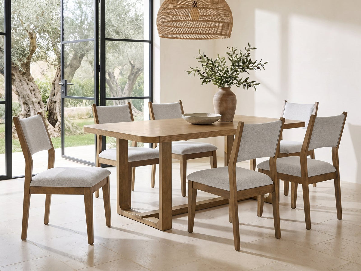 Mileto 72-Inch Light Oak Trestle Dining Set with 6 Upholstered Chairs in a sunlit villa dining area with olive trees outside