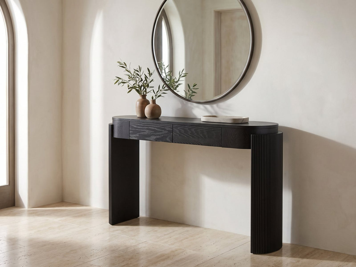 Minervino Black Oak Fluted Racetrack Console Table under a round mirror in a travertine entryway