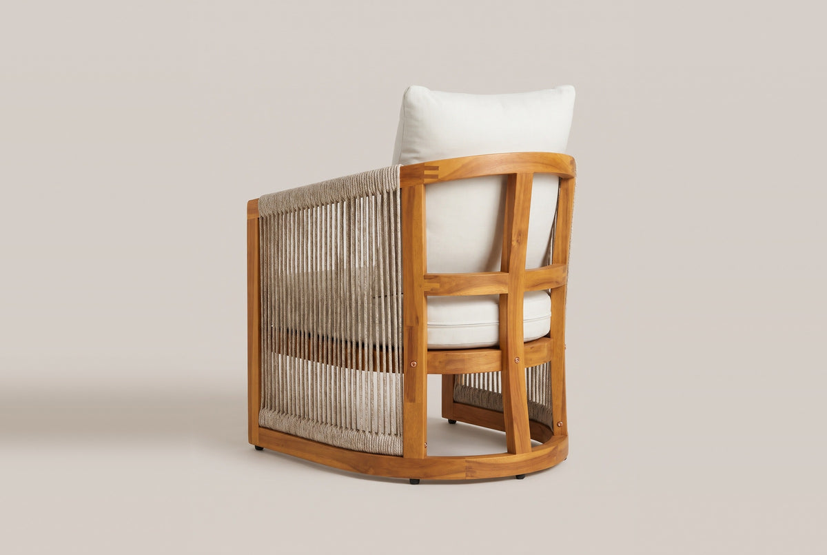 The Mondello club chair from behind: a curved acacia top rail, an open arched back with a centre post, the back cushion above and woven rope down the side
