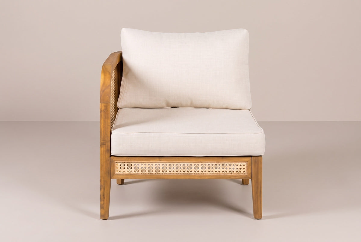 One Monreale arm chair from the front: the curved cane arm on the left, a cream back cushion and seat cushion, and a cane strip in the front rail