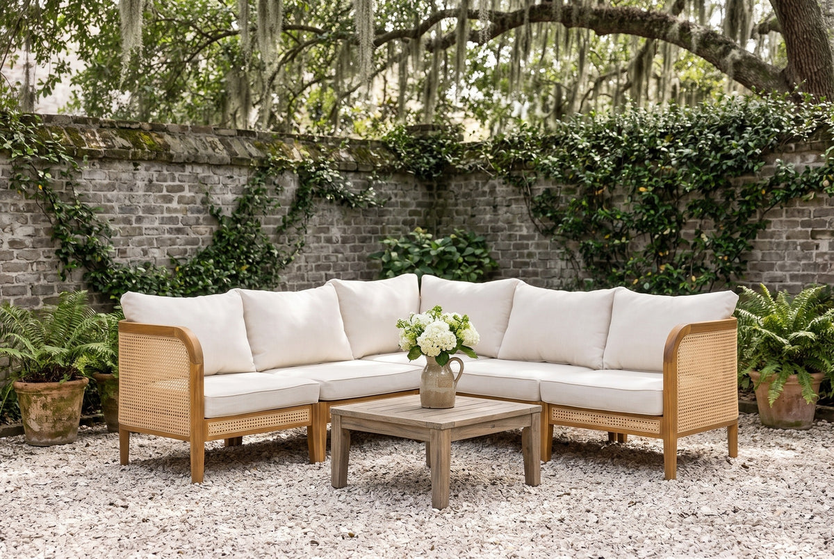 Monreale acacia and cane corner sectional on oyster-shell gravel in a Savannah, Georgia courtyard, an old grey brick wall with ivy and a live oak behind (coffee table not included)