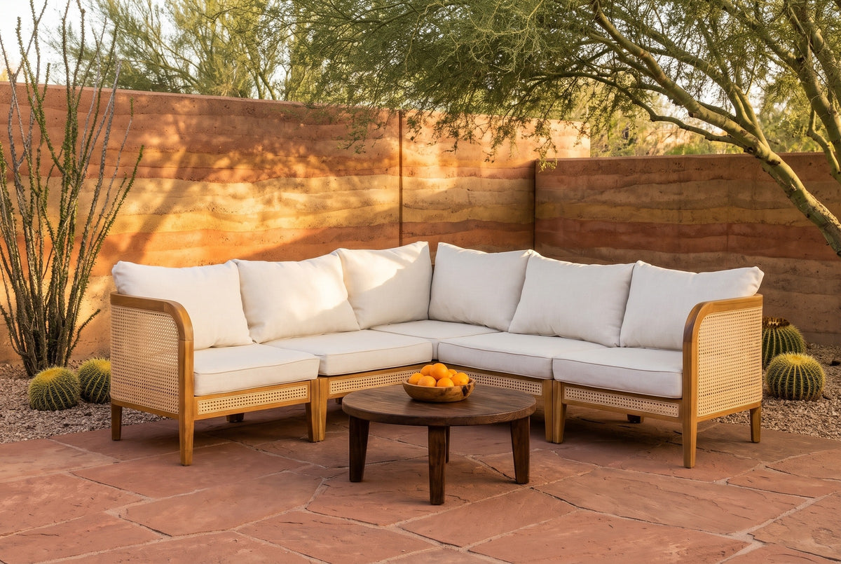 Monreale acacia and cane corner sectional in a Tucson, Arizona courtyard at golden hour, a banded rammed-earth wall, red flagstone and a palo verde tree (coffee table not included)