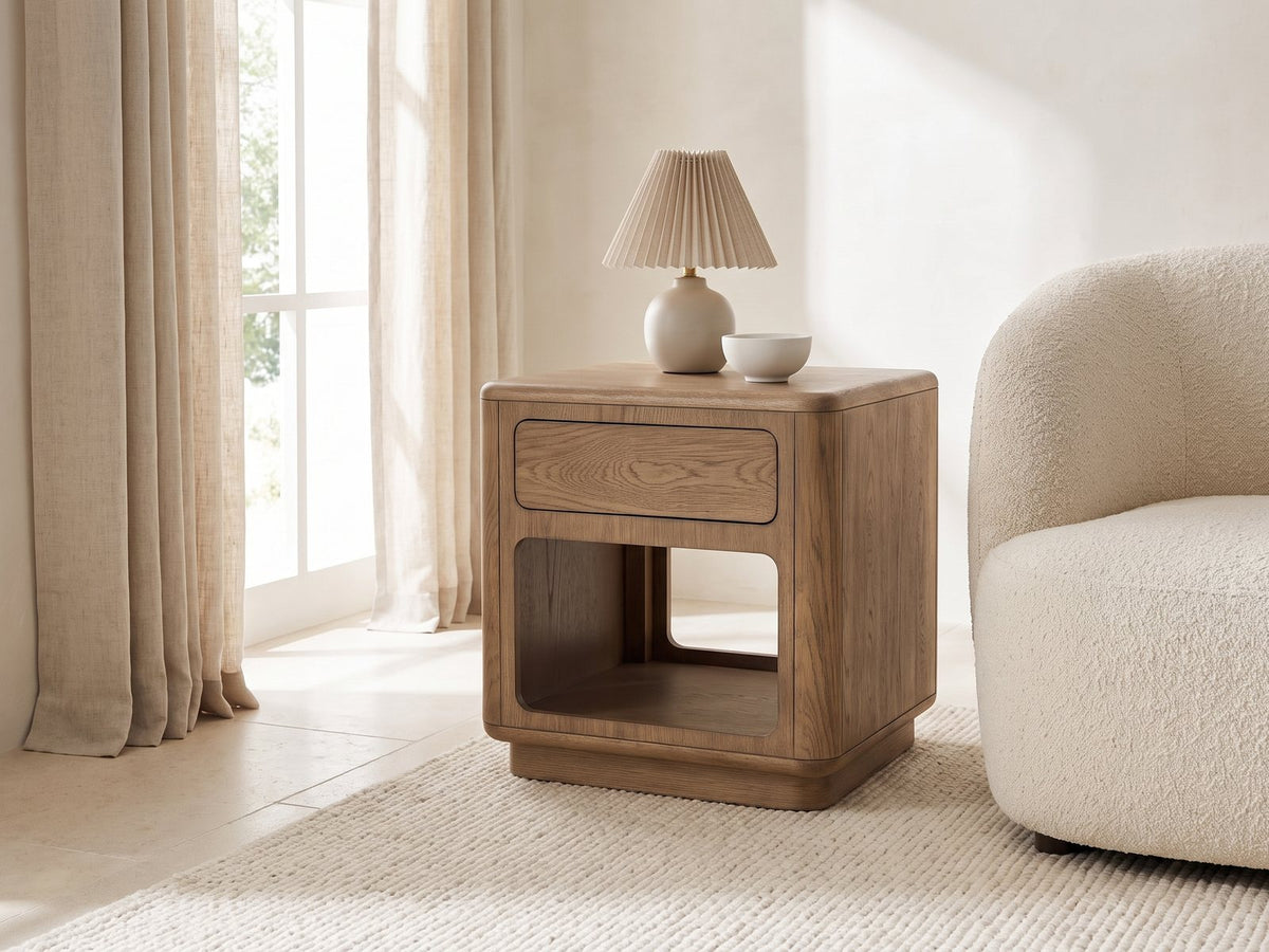 Monticchiello Driftwood Oak Veneer Cube Side Table with a lamp and a ceramic bowl beside a cream boucle armchair in a bright plaster room