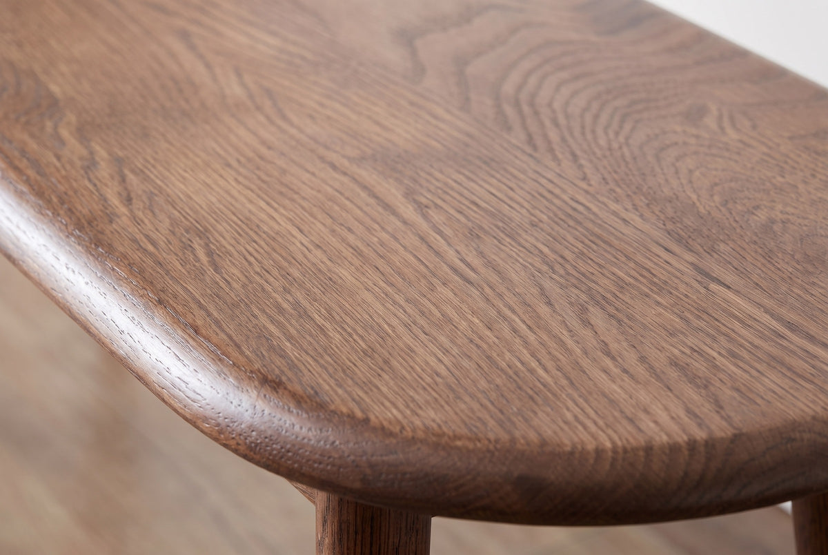 Close-up of the walnut-stained solid oak on the Montone bench: open grain running to the softly rounded edge of the top