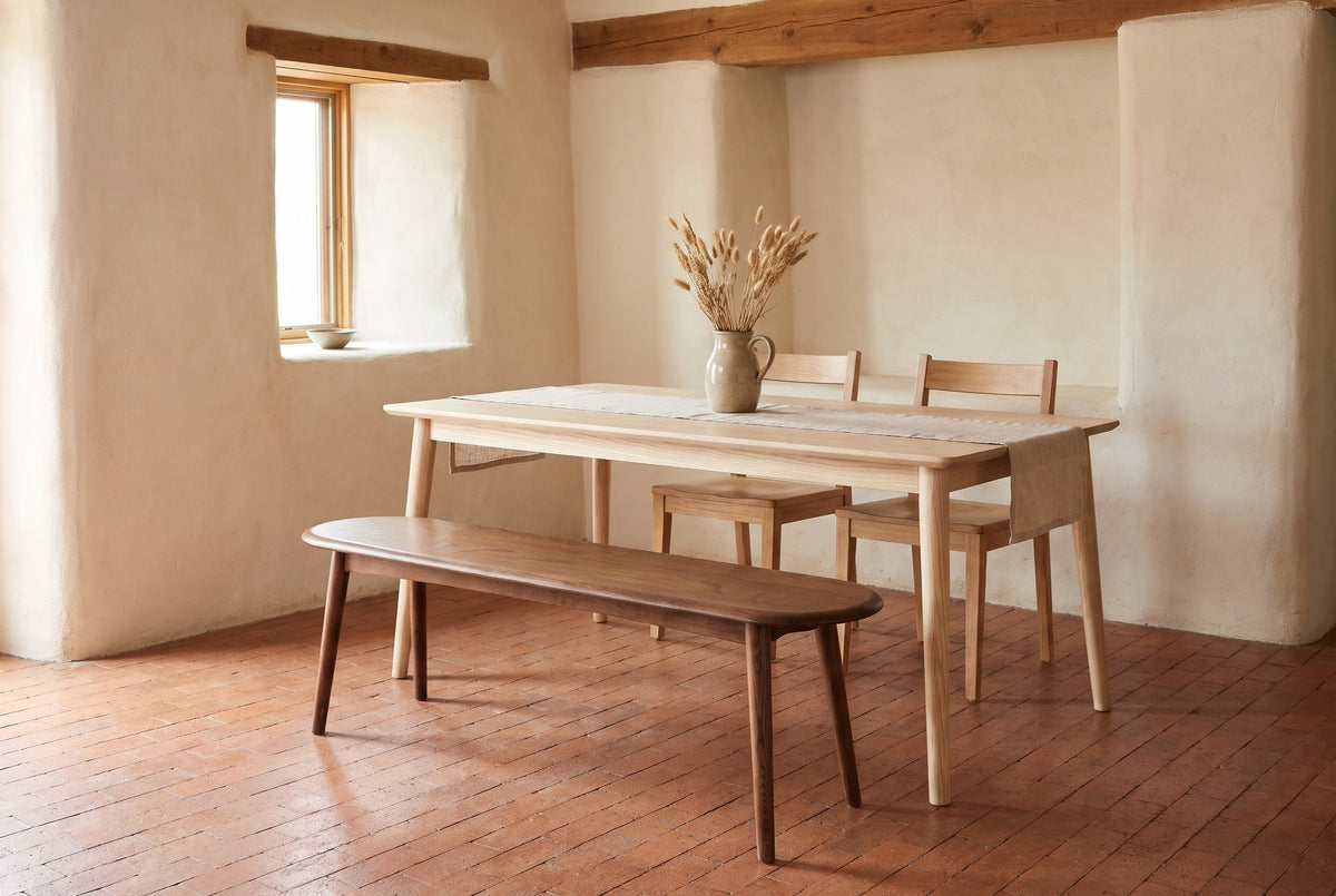 Montone walnut-stained oak bench along a pale ash dining table in a Santa Fe dining room with a cream adobe wall and a terracotta tile floor (table and chairs not included)