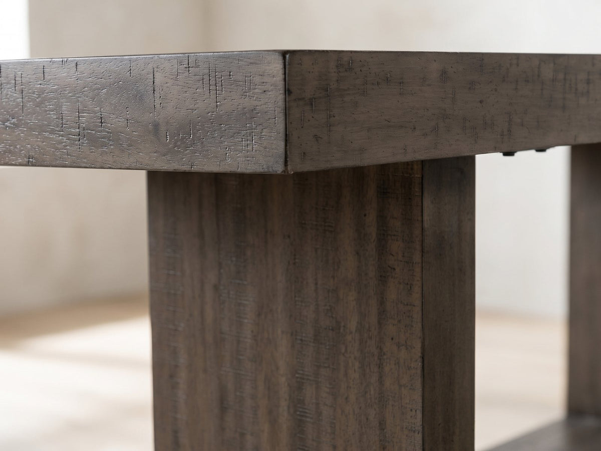 Close-up of the Mormanno 76 to 96-Inch Extending Brown Acacia Dining Set with 4 Chairs: the thick saw-marked acacia top and one upright of the box-frame base
