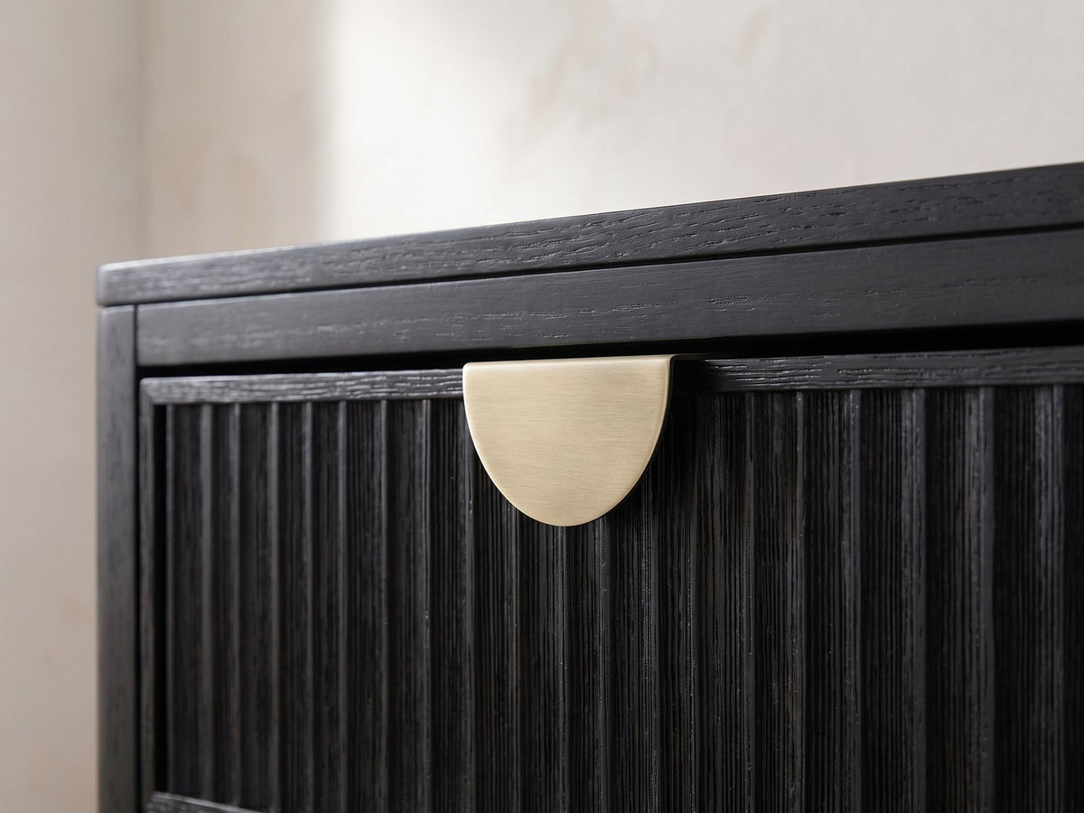 Close-up of the Murano 66-Inch Black Oak 8-Drawer Dresser with Mirror: a brushed antique-gold half-moon pull at the top edge of a reeded black oak drawer
