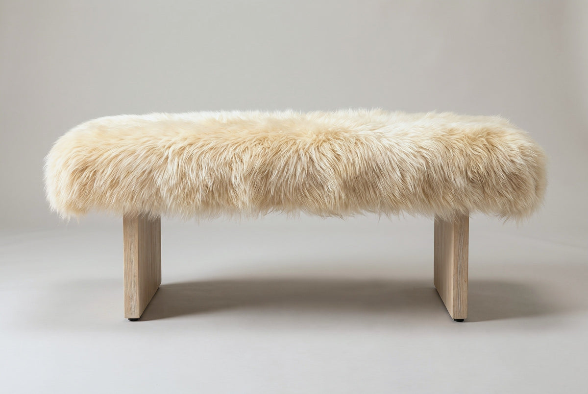 The Narni bench in natural blonde sheepskin, front view on a light studio backdrop