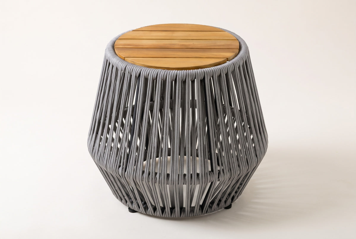 The Naro side table, three-quarter view: a round slatted acacia top over a flared grey rope body, on a light studio backdrop