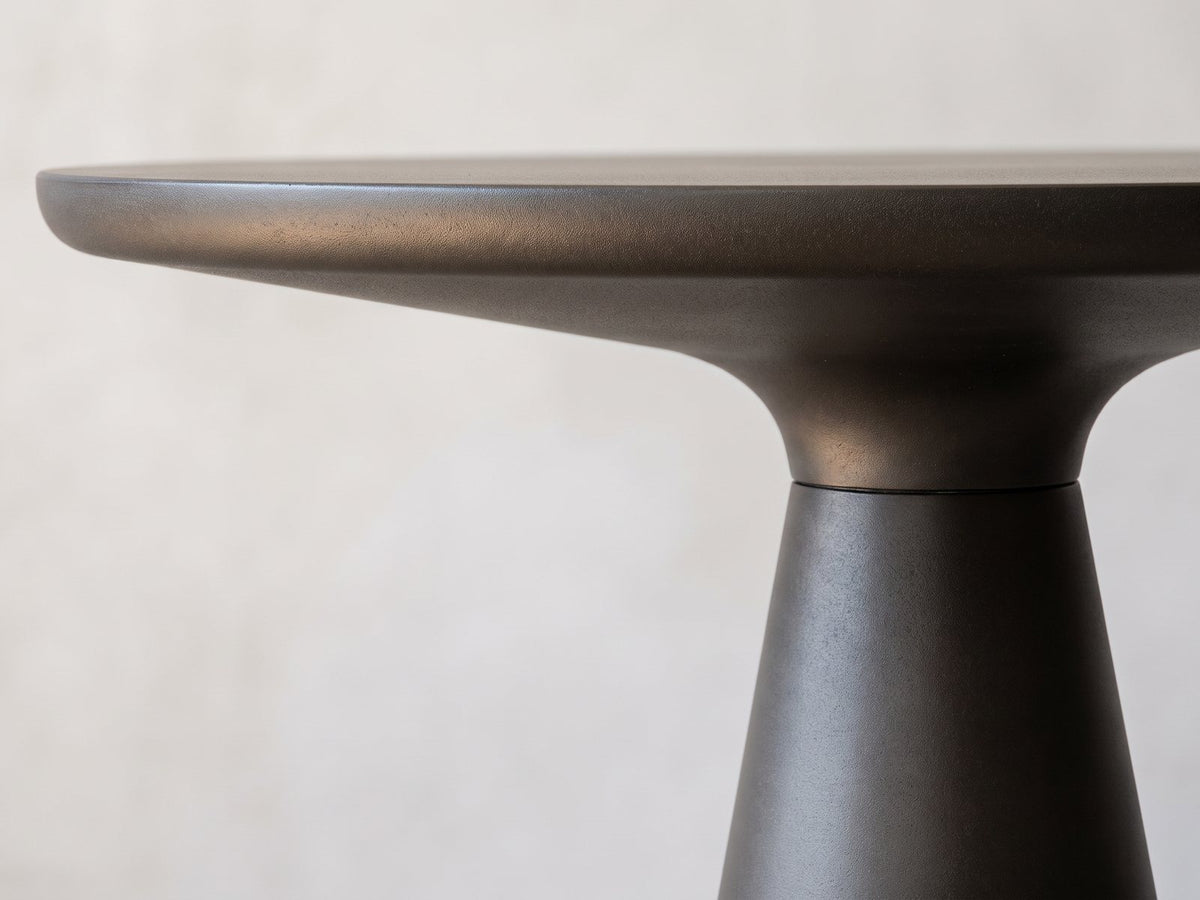Close-up of the Navelli Graphite Cast Aluminum Pedestal Side Table: the rounded edge and coved underside of the graphite top