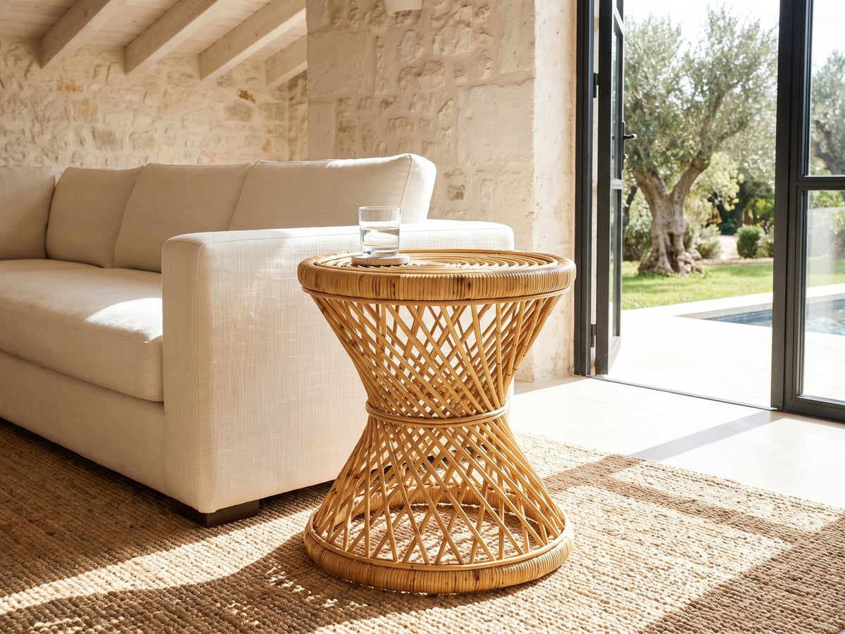 Neviano Natural Rattan Hourglass Side Table beside a linen sofa in a poolside villa