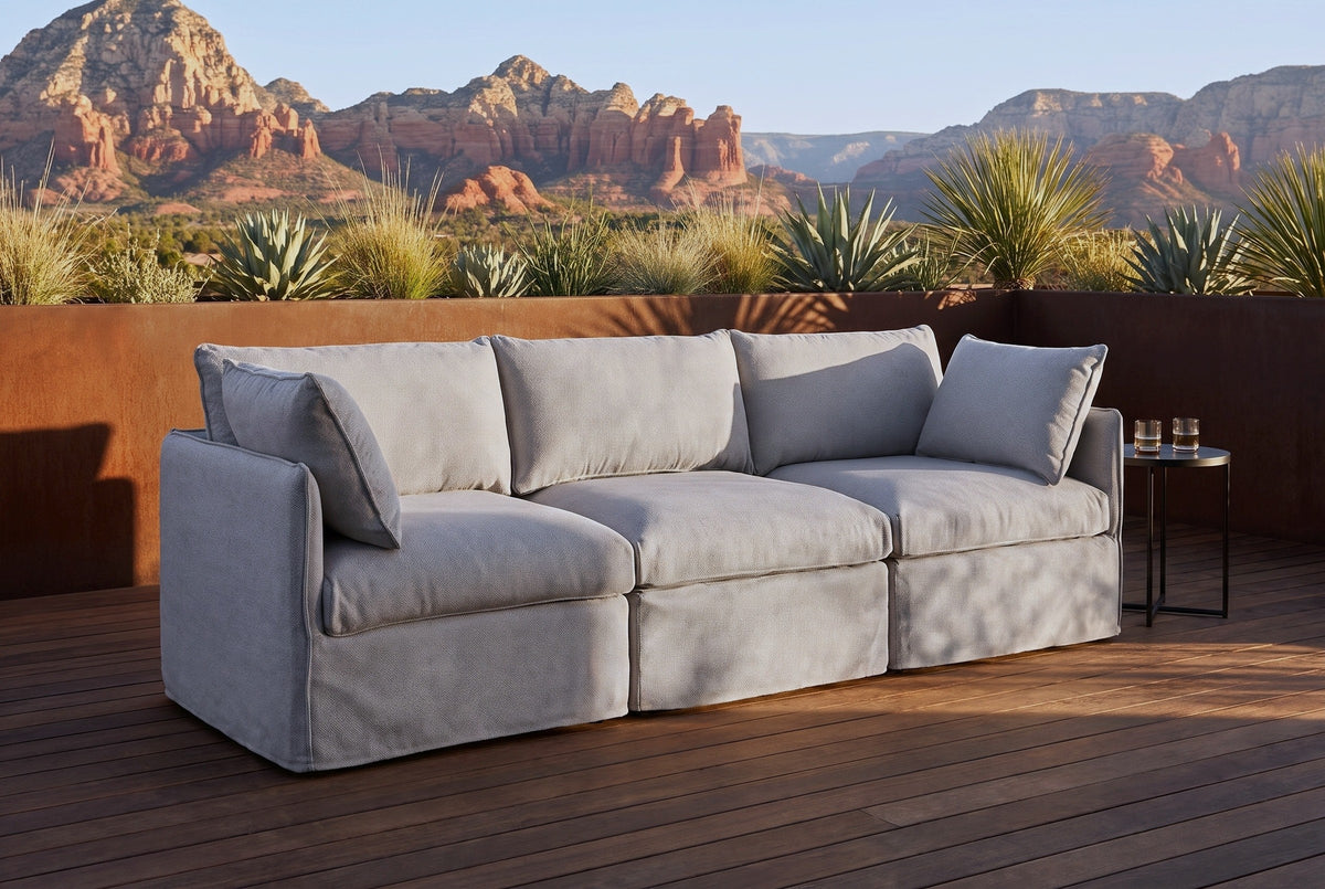 Nicosia grey slipcovered outdoor sofa on a dark hardwood deck in Sedona, a Corten steel planter wall and red rock buttes behind (side table not included)