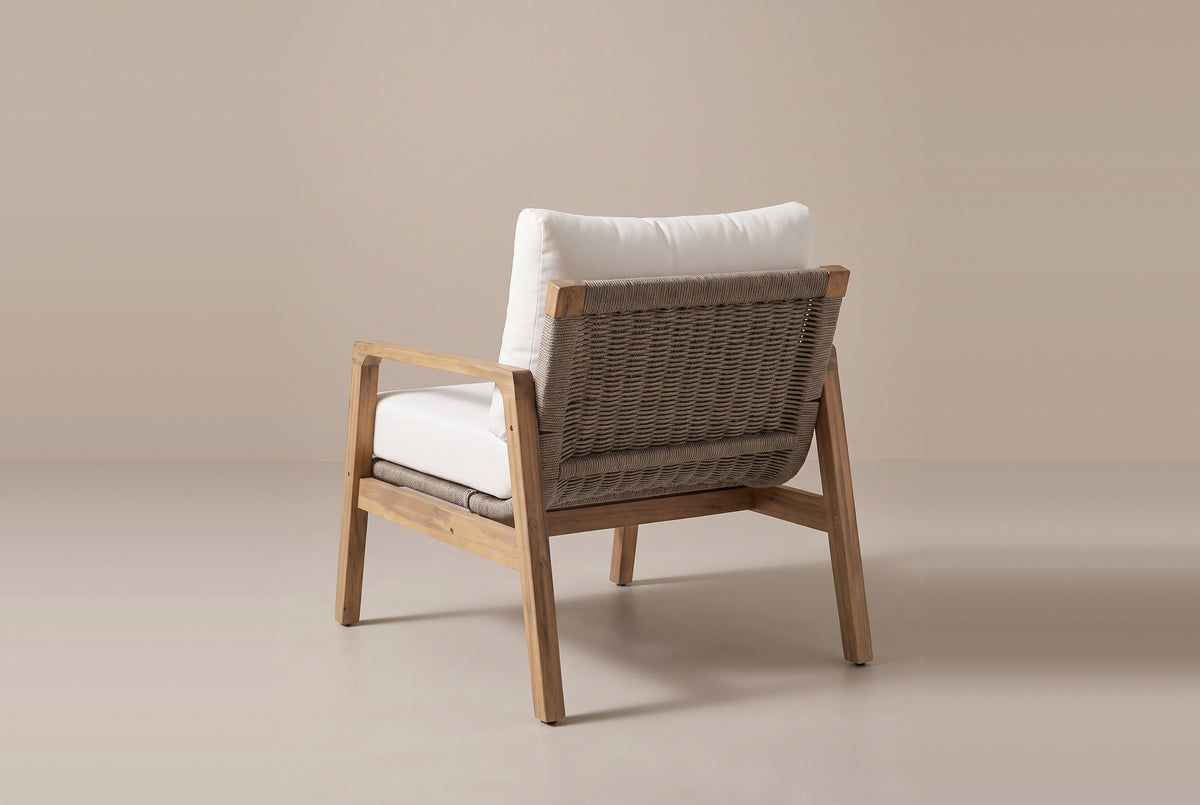 The Niscemi chair from behind: the woven rope back stretched between angled acacia posts, raked back legs and side stretchers