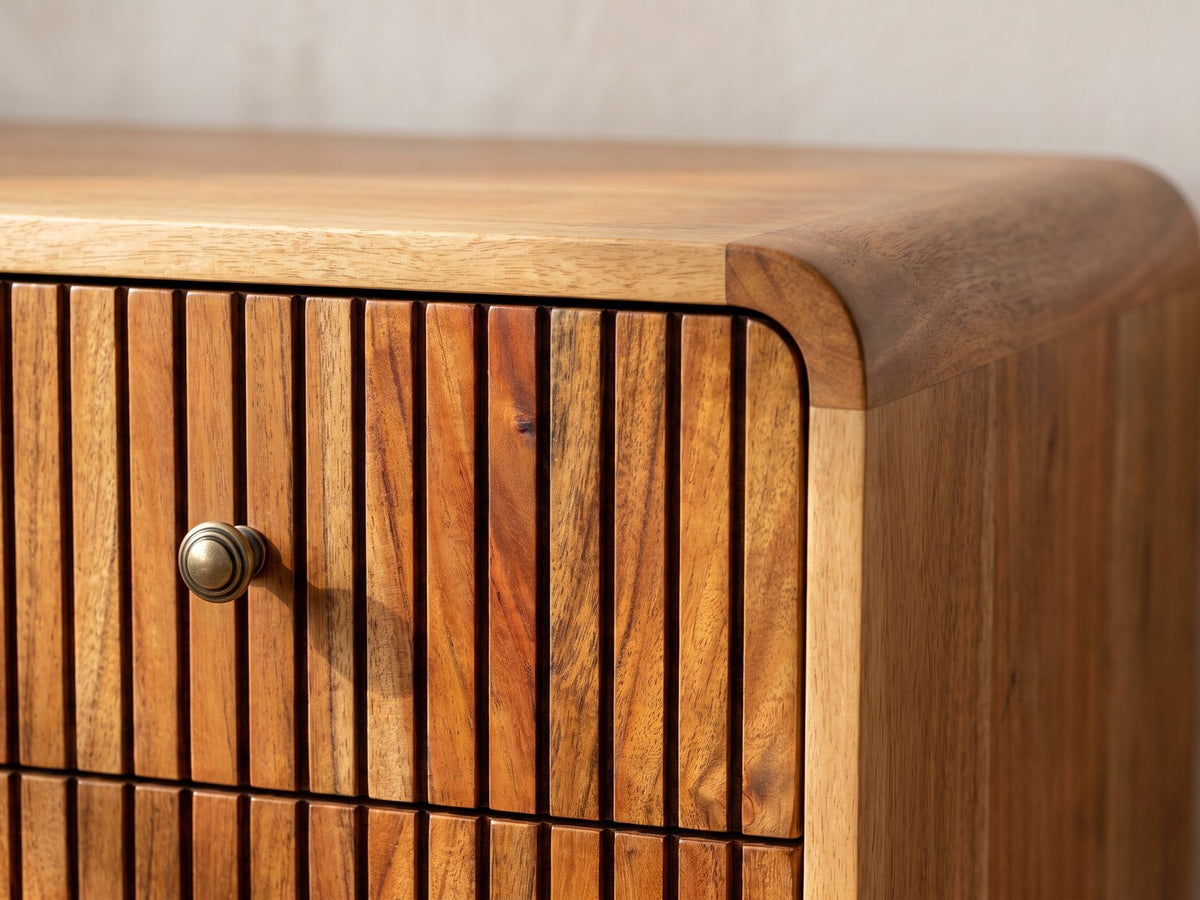Close-up of the Noale 28-Inch Honey Caramel Solid Mango 3-Drawer Chest: the rounded corner of the case above the ribbed top drawer and its antique-brass knob