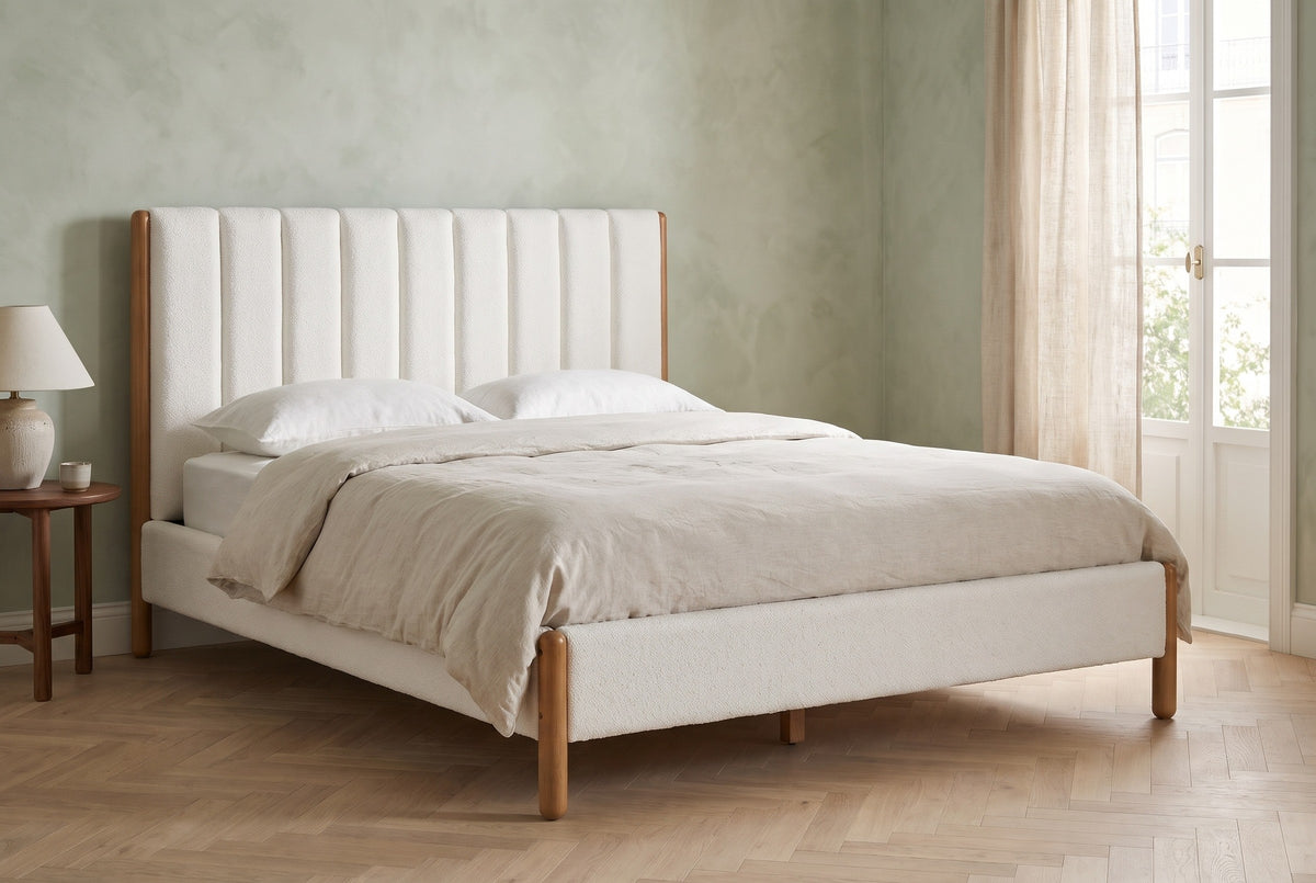 Ofena white boucle bed against a sage-green limewash wall in a Lisbon apartment bedroom with a tall window, a linen curtain and a herringbone floor