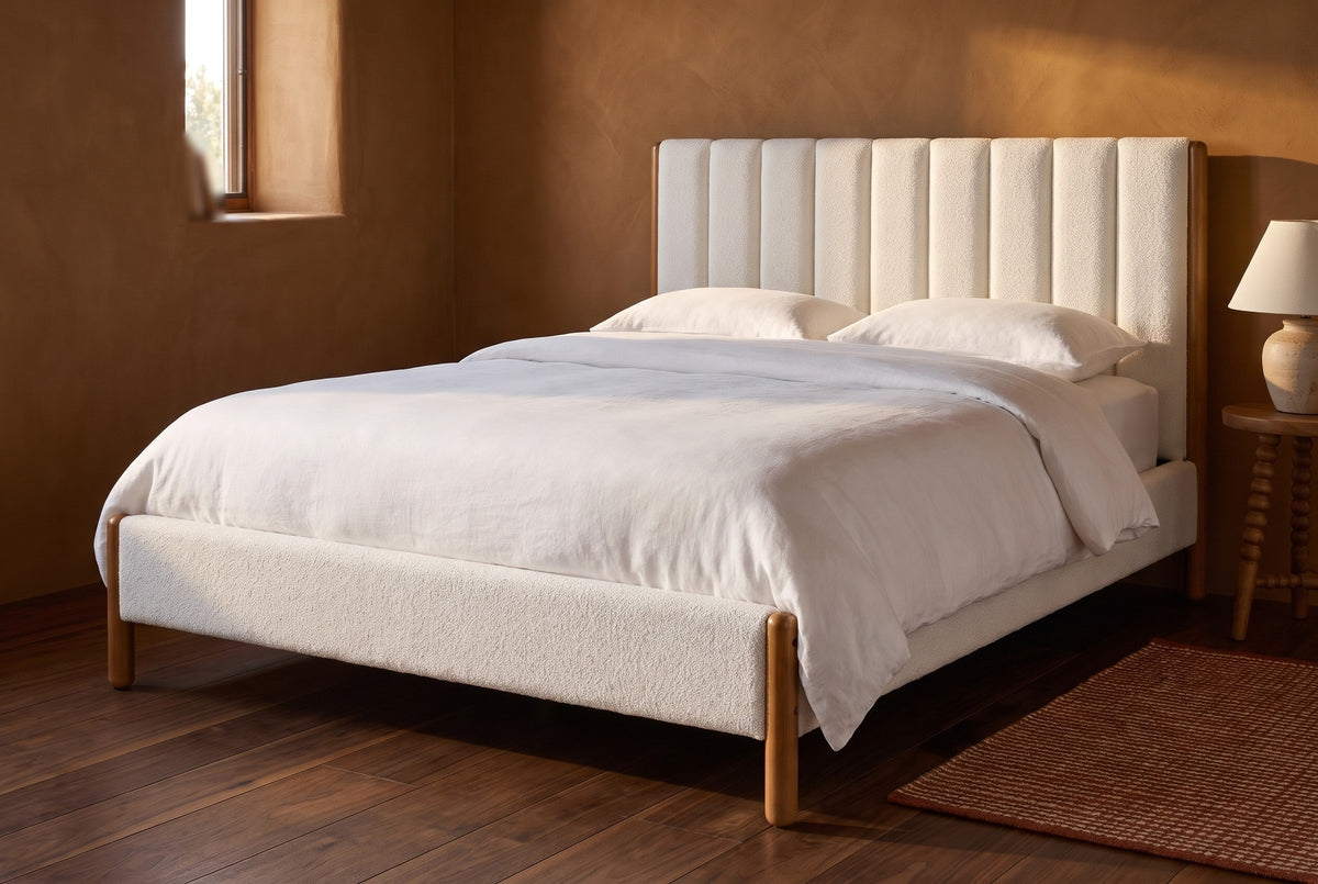 Ofena white boucle bed against a deep ochre clay plaster wall in a Taos adobe bedroom with a deep-set window and a walnut floor
