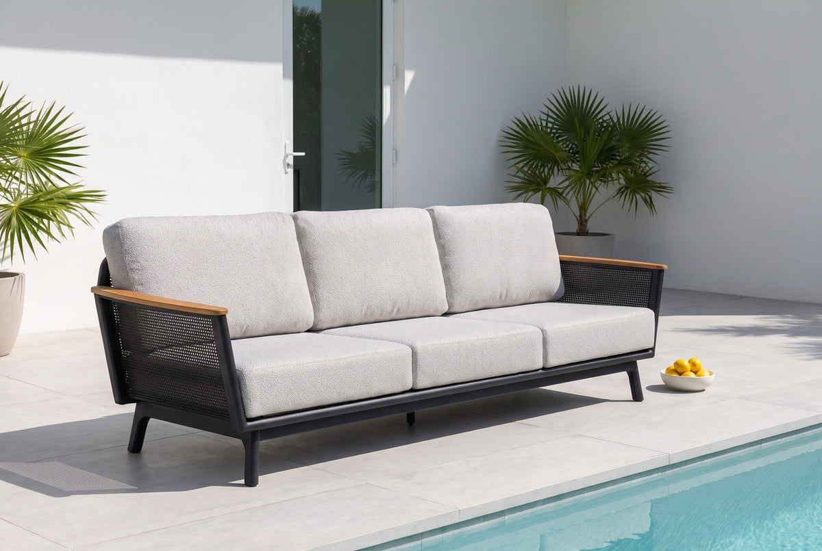 Ognina outdoor sofa on pale porcelain pavers beside a pool at a modern house in Miami Beach, a white stucco wall and potted palms behind (bowl not included)