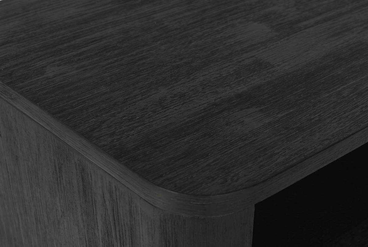 Close-up of the Olbia nightstand: black wire-brushed acacia with fine grey grain lines and a softly rounded top edge