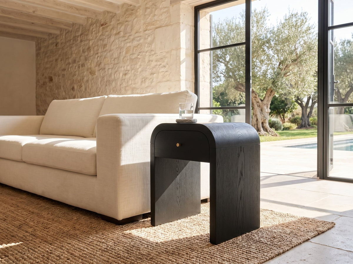 Oppido Black Ash Veneer Waterfall Side Table beside a linen sofa in a poolside villa