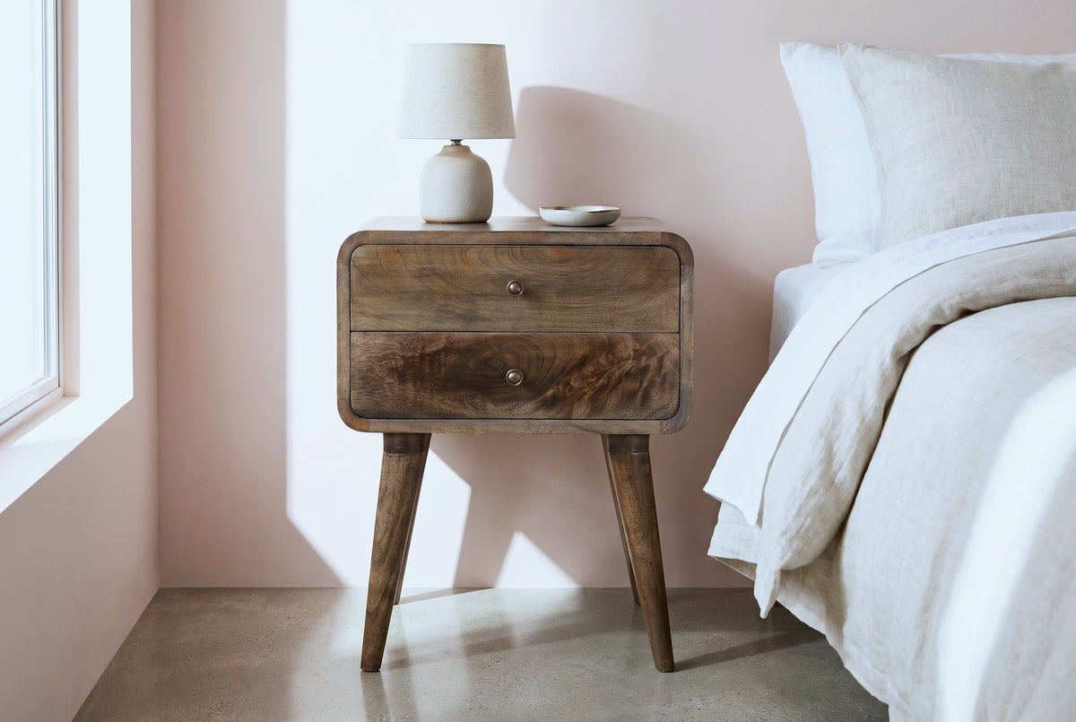 Oristano grey-washed mango nightstand against a soft blush pink plaster wall in a Palm Springs bedroom with a polished concrete floor