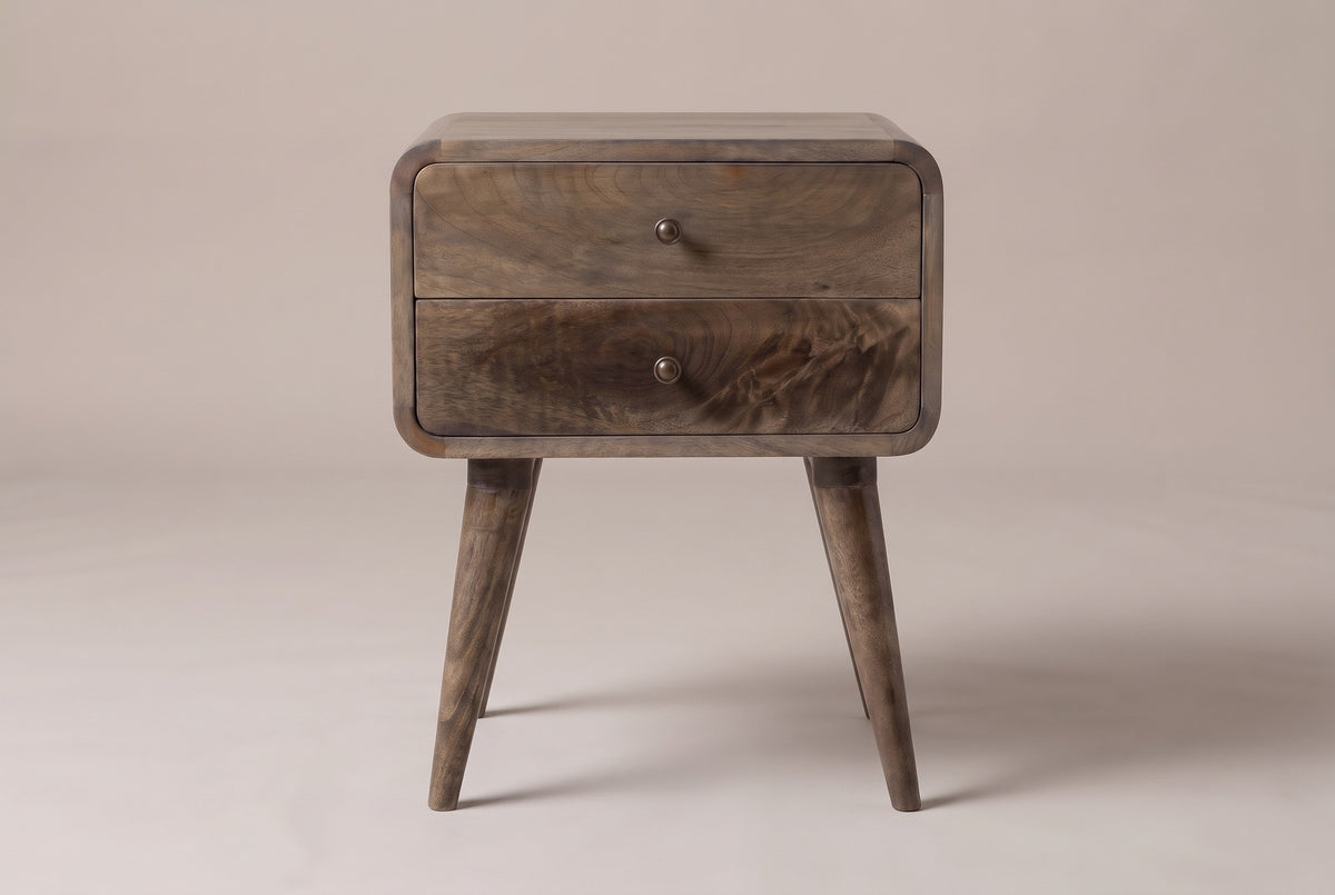 The Oristano two-drawer nightstand in grey-washed mango with bronze-tone knobs, rounded corners and four splayed round legs, straight front view on a light studio backdrop