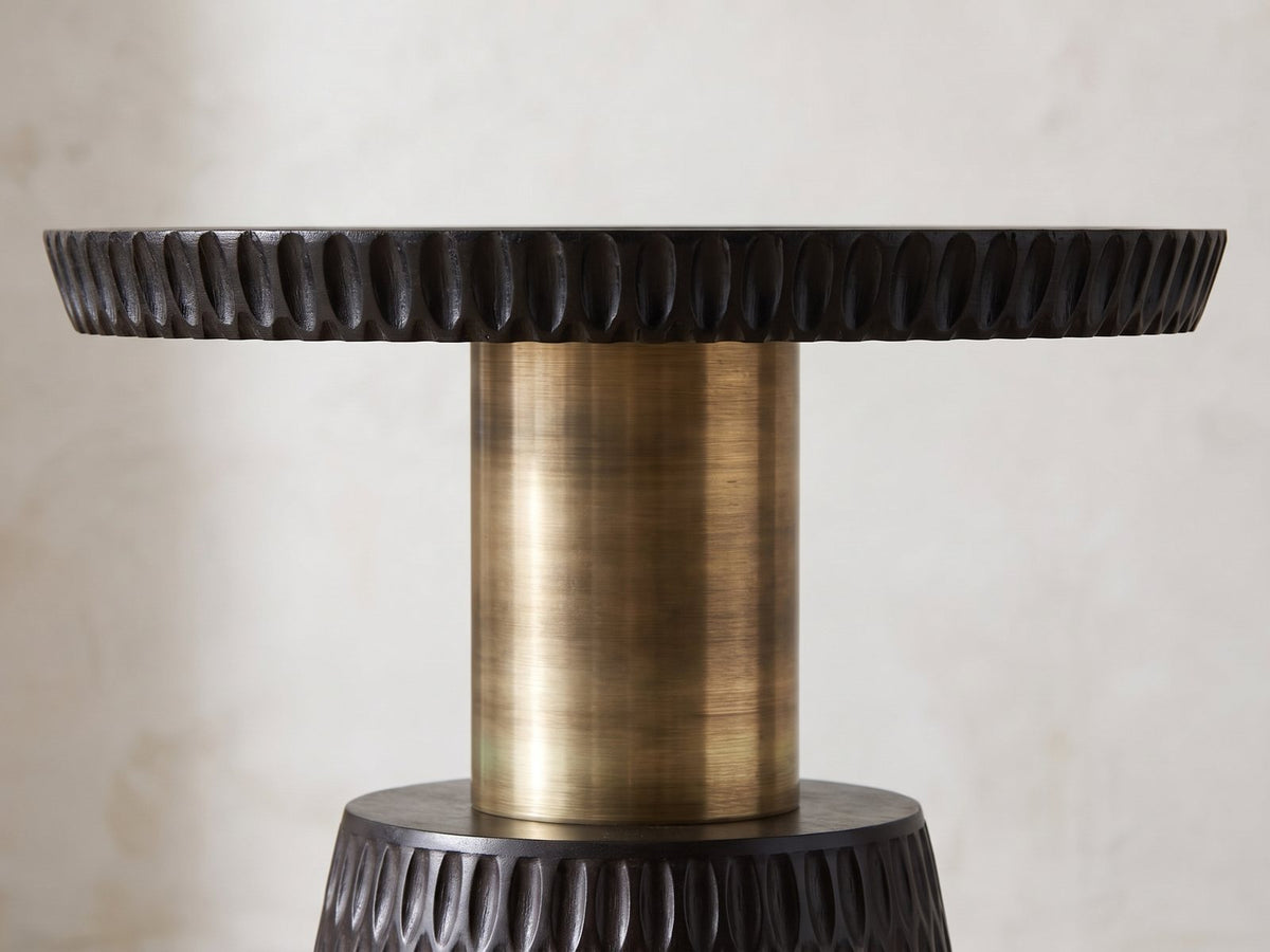 Close-up of the Orsomarso Carved Black Mango Pedestal Side Table: the carved tray edge over the antique-gold metal stem