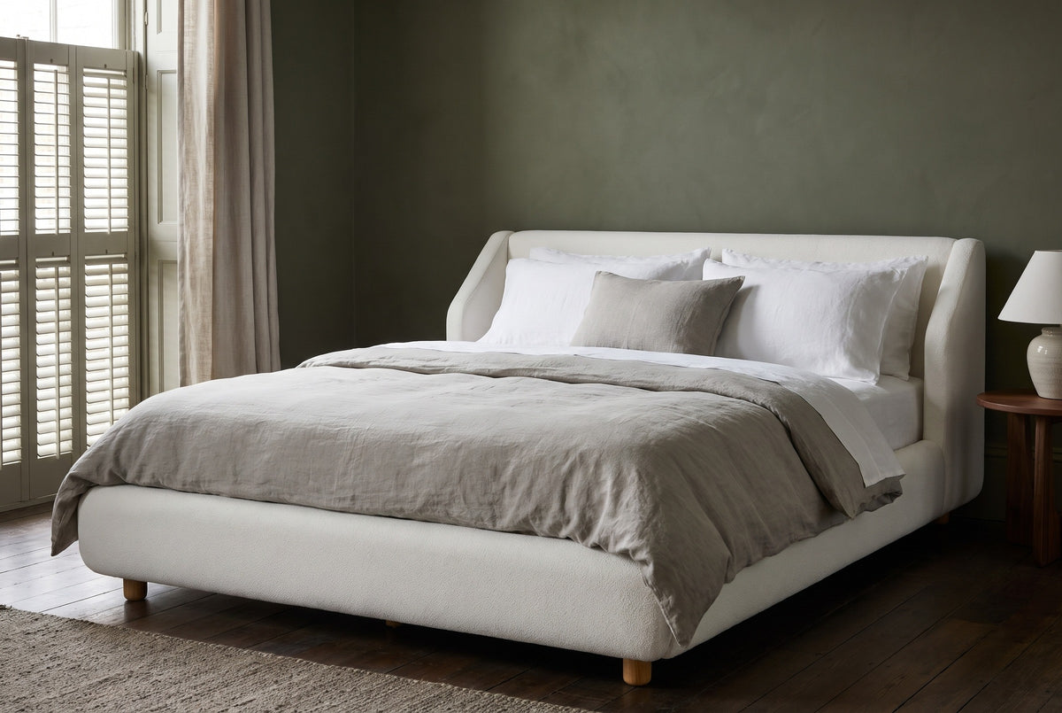 Pacentro bed against a deep olive-green limewash wall in a New Orleans townhouse bedroom with dark oak floorboards and a shuttered window