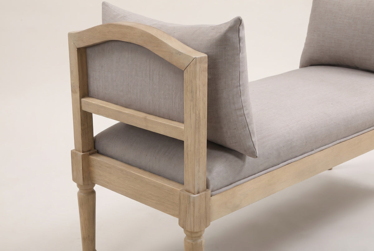 One end of the Paciano bench: the open arm with its arched top rail, greige panel and mid-rail, the corner block, the seat edge and a pillow leaning on the arm