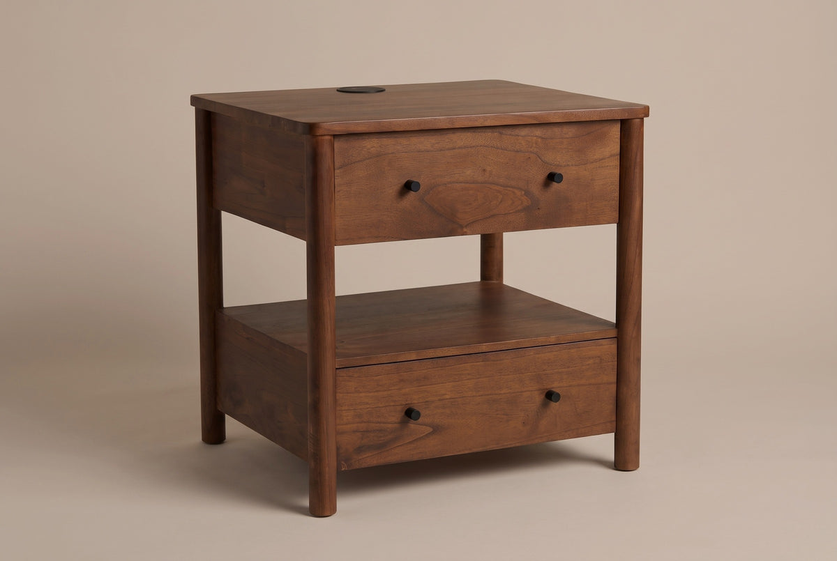 The Palau two-drawer nightstand in warm brown solid neem with an open shelf and a wireless charging pad in the top, three-quarter view on a light studio backdrop