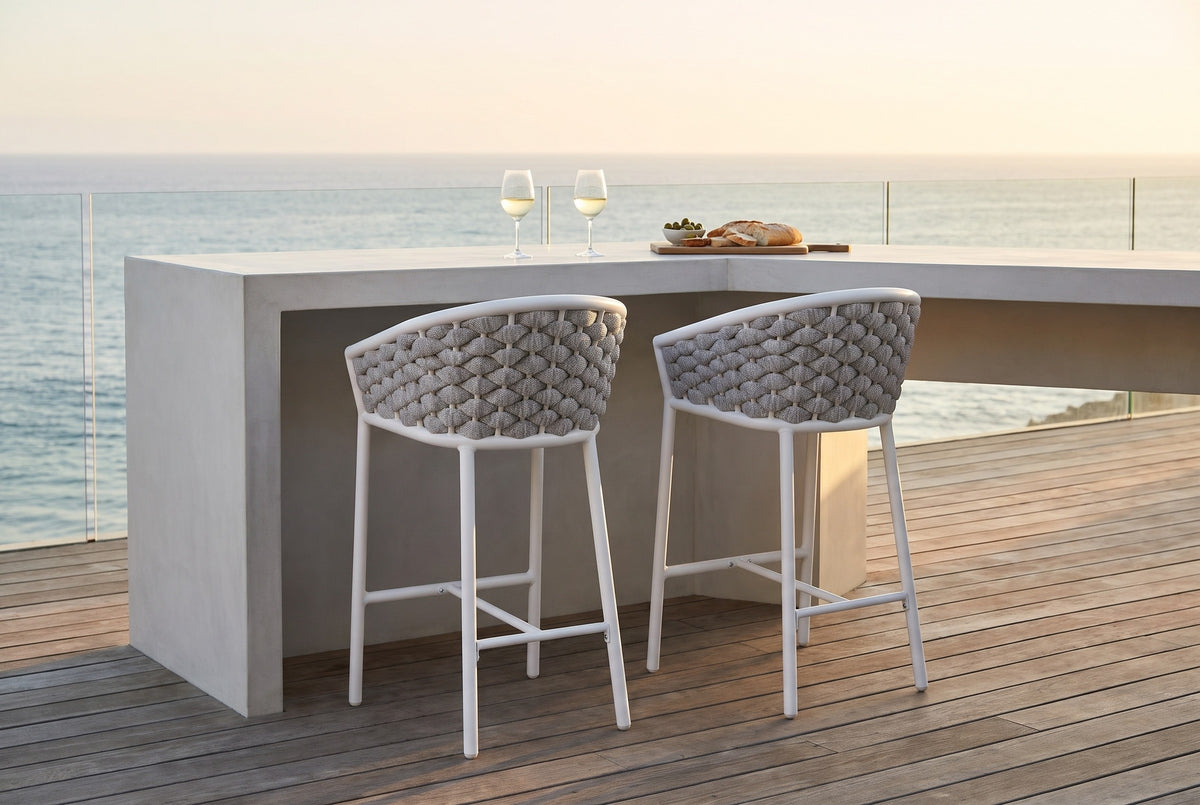 Two Petralia counter stools with grey rope backs at a pale concrete counter on a teak-decked ocean-view terrace in Laguna Beach at golden hour (counter not included)