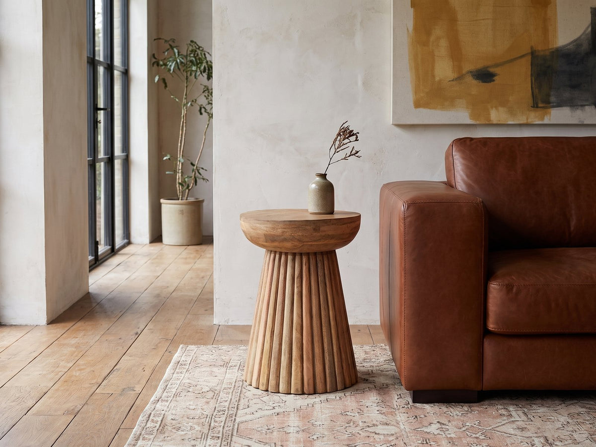 Petroio Fluted Mango Mushroom Side Table beside a leather sofa in an industrial loft