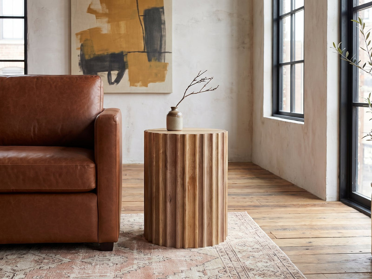 Pisticci Solid Mango Fluted Drum Side Table beside a cognac leather armchair in an industrial loft