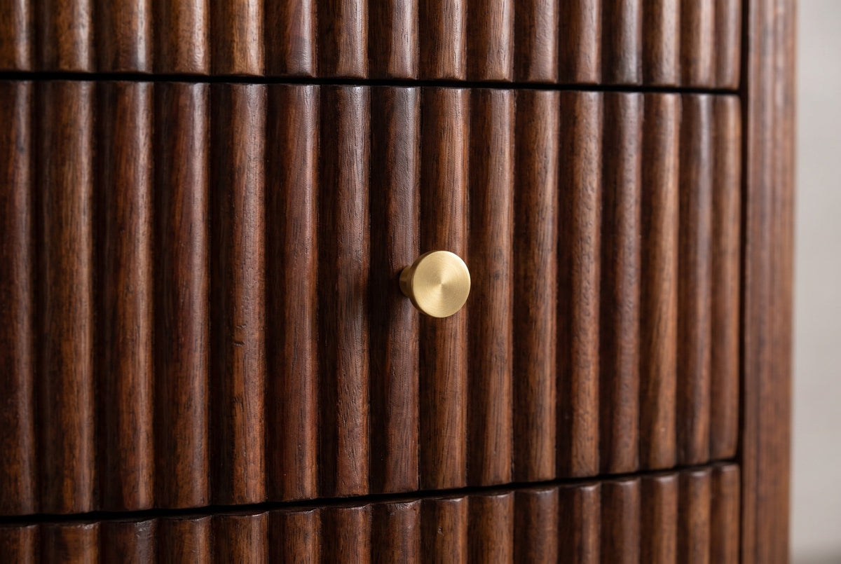 Close-up of a Ploaghe drawer front: fine vertical reeds in chestnut mango wood and one round brass-style knob