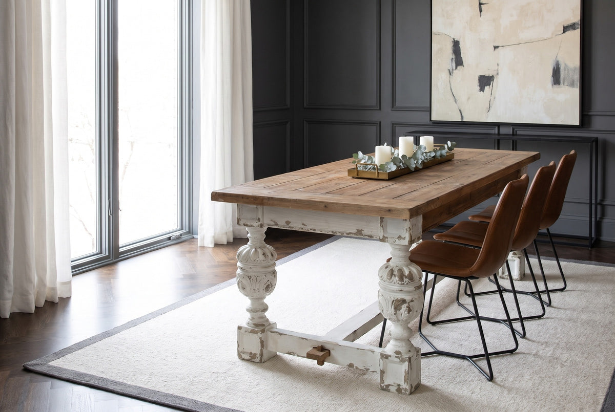 Policoro fir plank dining table with carved antique-white urn legs in a Chicago dining room with a charcoal panelled wall, a white wool rug and a walnut herringbone floor