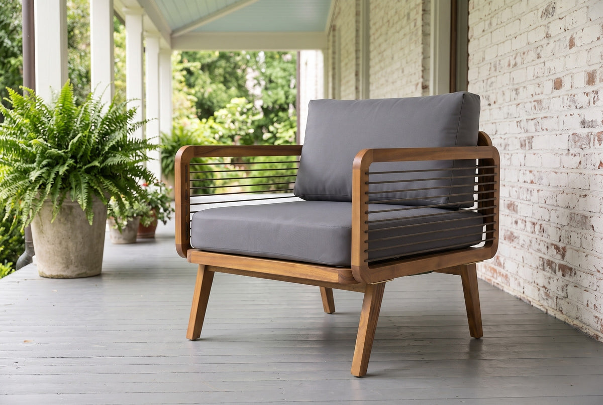 Polizzi acacia lounge armchair on a covered porch in Wilmington, North Carolina, with a whitewashed brick wall, grey porch boards and potted ferns (planters not included)