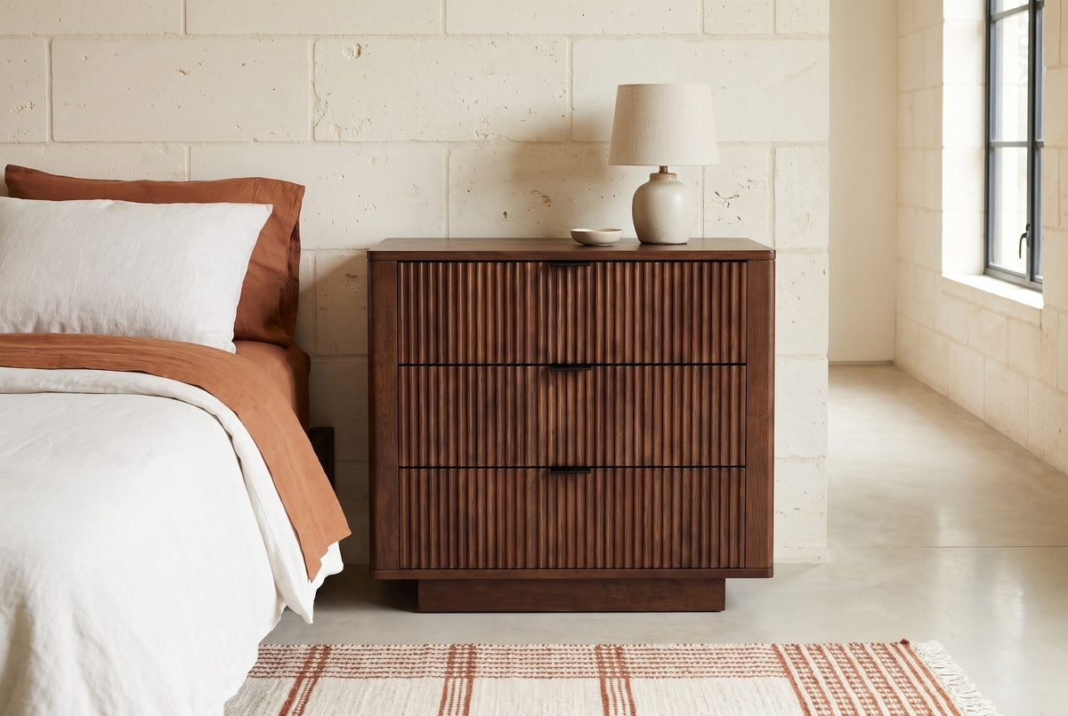 Pula reeded walnut nightstand against a pale limestone wall in an Austin Hill Country bedroom with a polished concrete floor