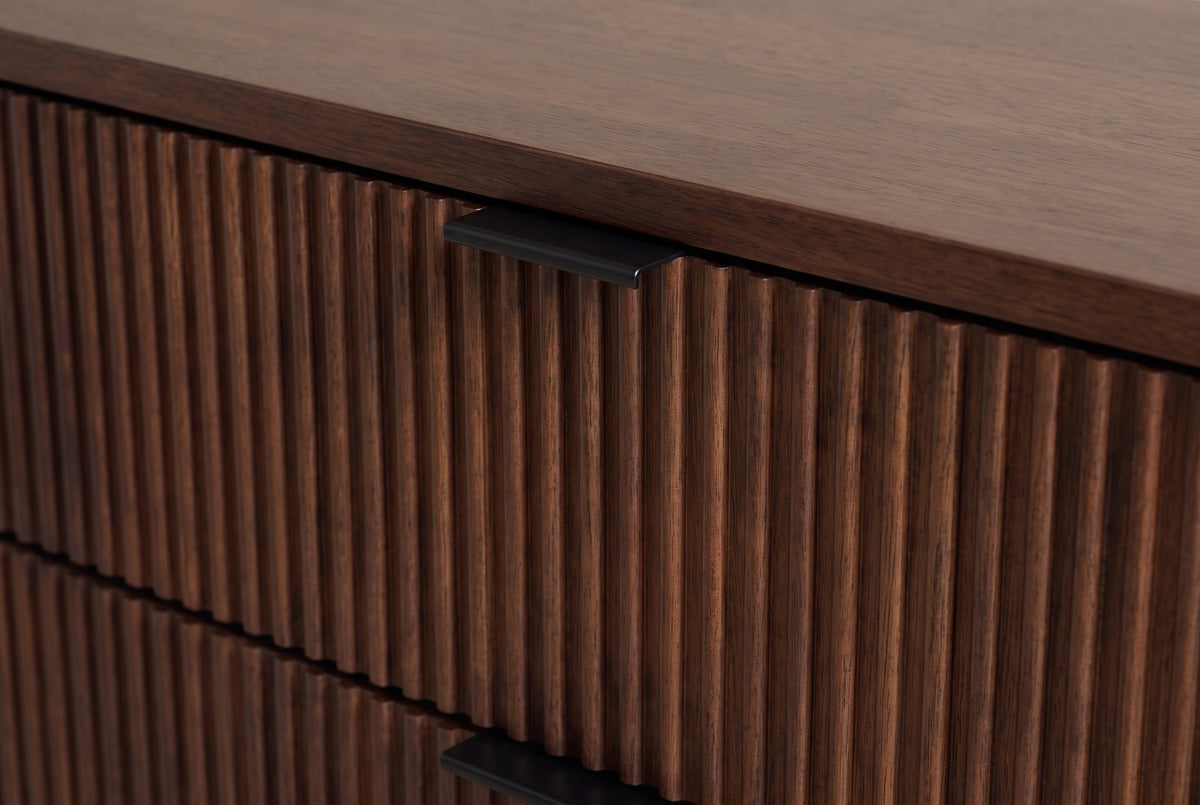 The top drawer of the Pula nightstand: narrow vertical walnut reeds and the matte black tab pull folding over its top edge