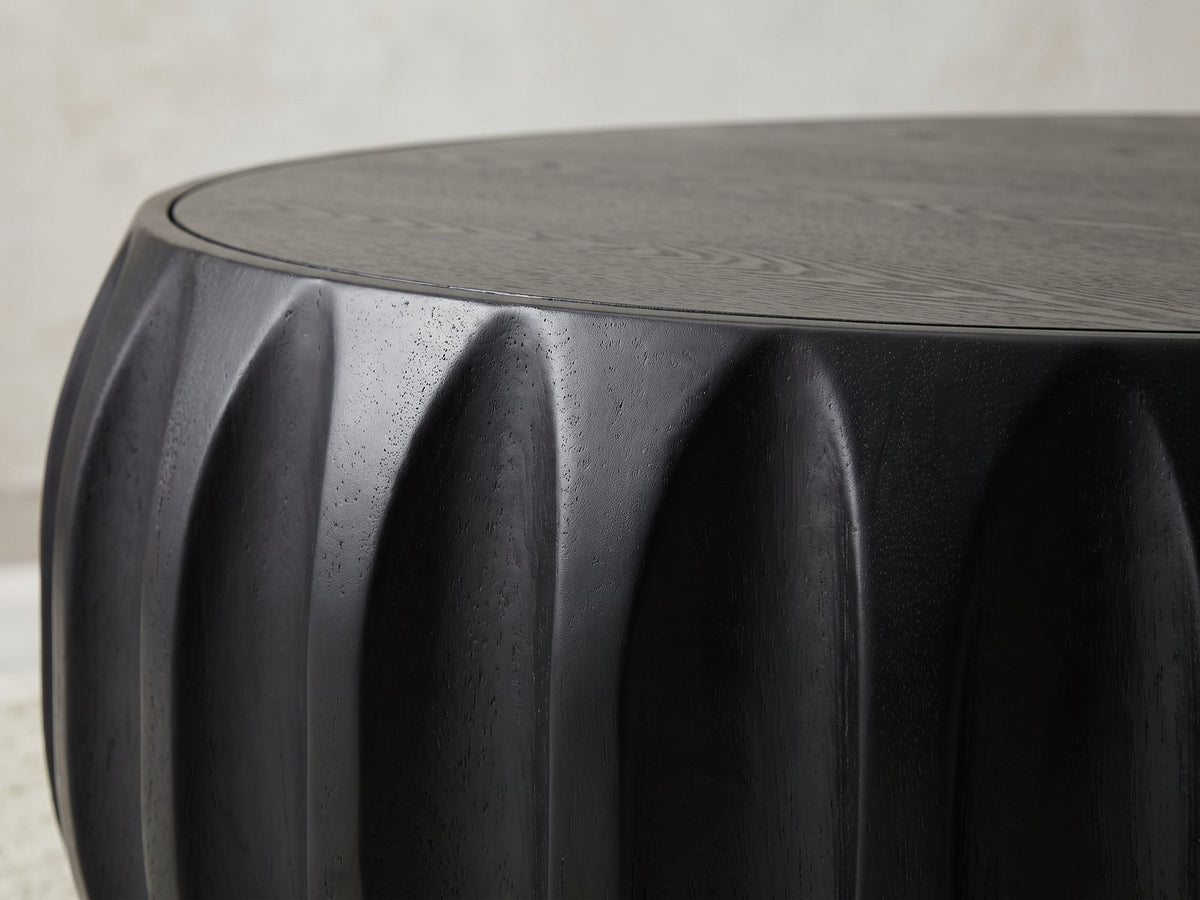 Close-up of the Radda Black Carved Wood Drum Coffee Table: the carved black wood scallops under the rim of the top