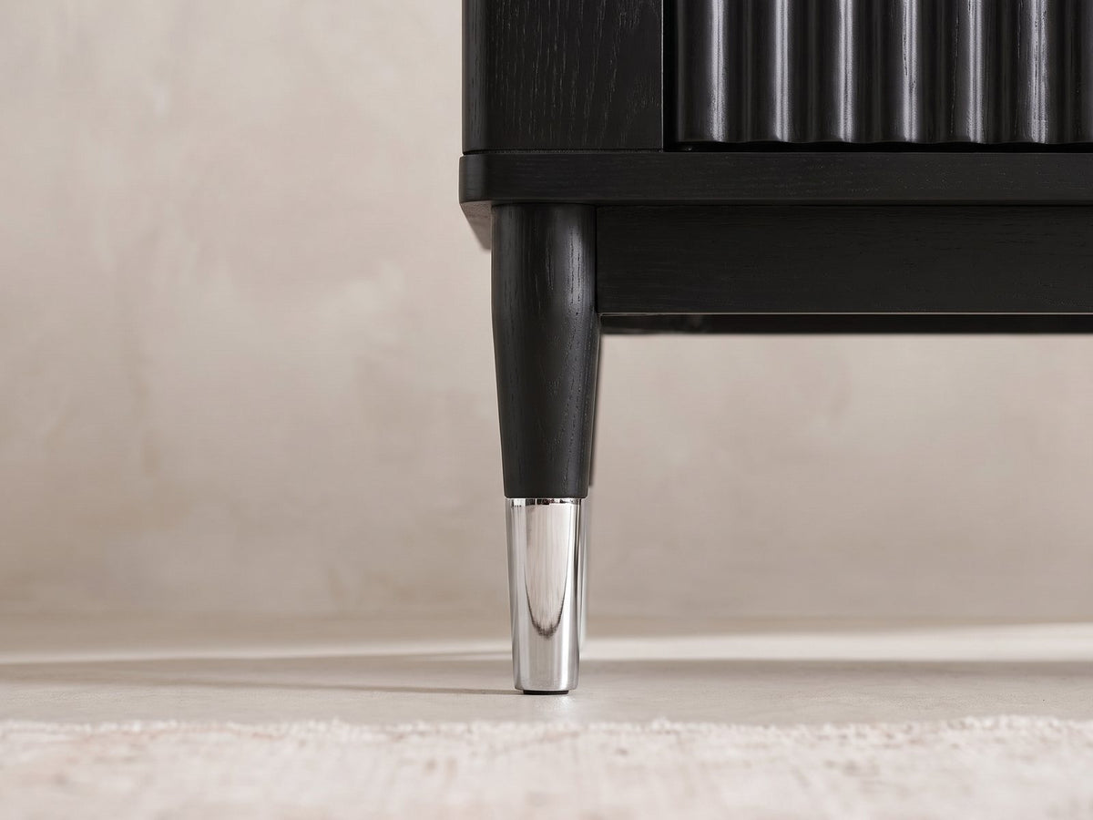 Close-up of the Ragusa Stone Top Media Console: a black tapered leg with its chrome cap