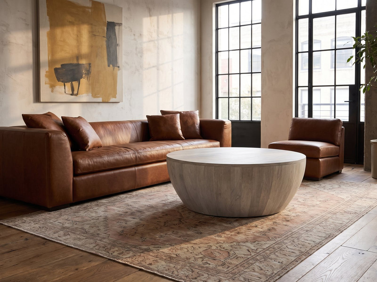 Rapallo Whitewashed Mango Bowl Coffee Table on a vintage rug in front of a leather sofa in an industrial loft