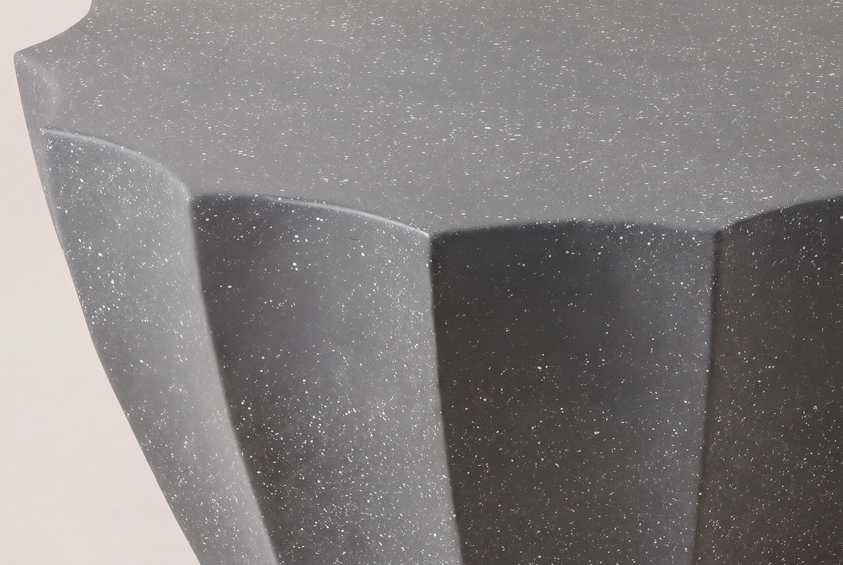 Close-up of the Ribera table: the speckled gray MgO cement at one point of the scalloped top, white flecks in the matte surface