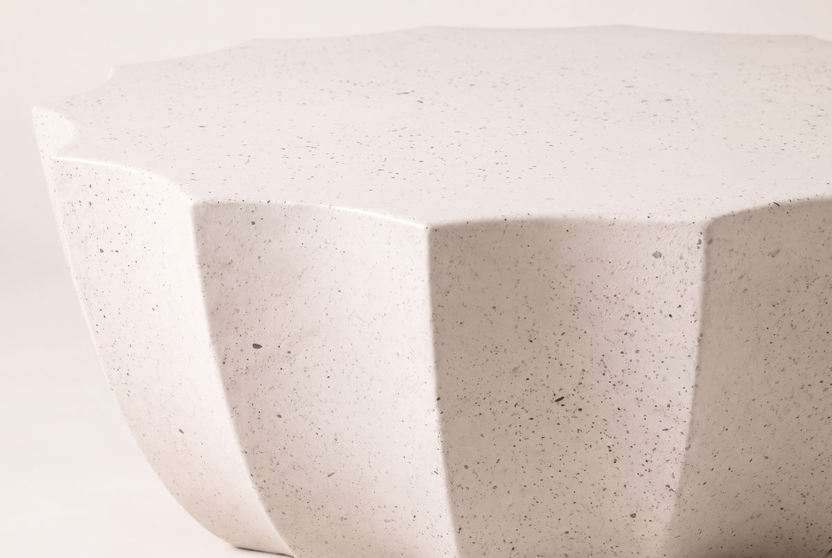 Close-up of the Ribera table in speckled white: dark flecks in the matte MgO cement at the points of the scalloped top and the concave flutes below